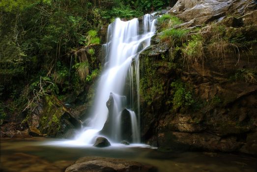 A waterfall surrounded by rocks and some vegetation.