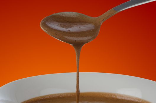 Chocolate mousse falling from spoon to white bowl.