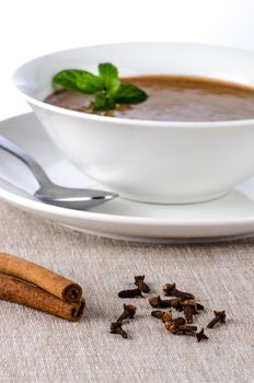 Chocolate mousse ou a white mug with mint leaves and spoon.