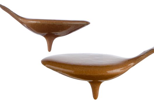 Liquid Chocolate dripping from two spoons on white background.