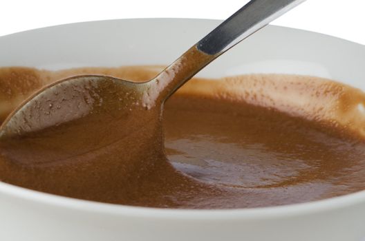 Chocolate mousse on a white mug with spoon on white background.