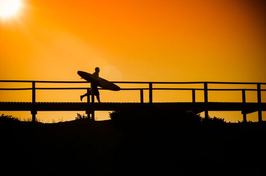 A surfer running to the beach at sunset in Portugal.