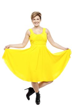 Attractive smiling female in bright summer dress. Holding her frock and wearing stilettos