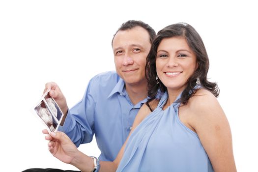 Attractive hispanic young pregnant couple expecting a child holding ultrasound