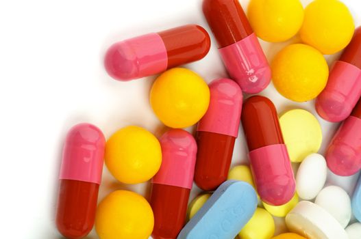 Heap of Pink, Red and Yellow Vitamin Pills closeup on white background