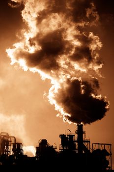 Smoking chimney  at sunset on industrial buildings complex.