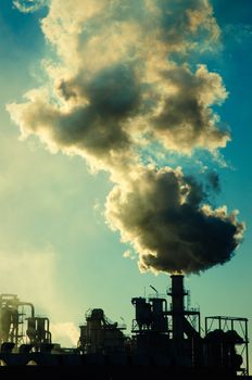 Smoking chimney  at sunset on industrial buildings complex.