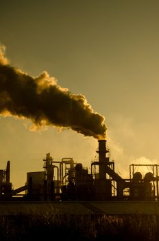 Smoking chimney  at sunset on industrial buildings complex.