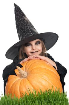 Portrait of little girl in black hat and black clothing with pumpkin on white background