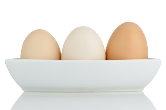 Brown eggs in white ceramic bowl isolated on white background.