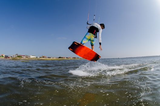 Kiteboarder flying over the water on a sunny day.