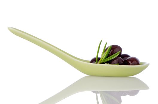 Olives on ceramic spoon with basil and olive oil