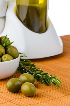 Green olives in a white ceramic bowl and oil decanter set.