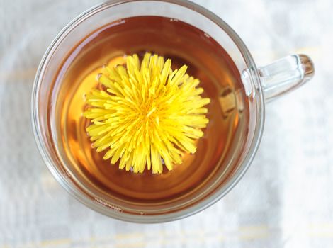 Herbal tea in glass cup and flowers on wooden table