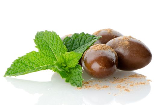 Chocolate candies on white reflective background.