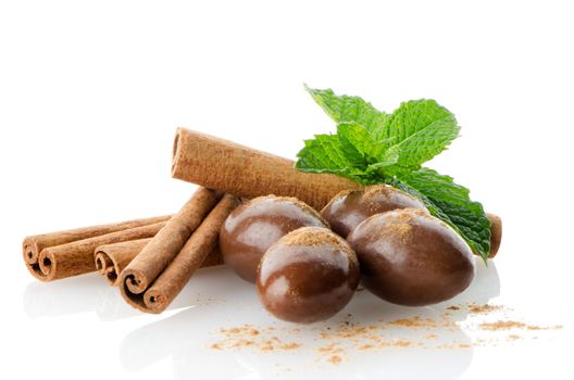 Chocolate candies on white reflective background.