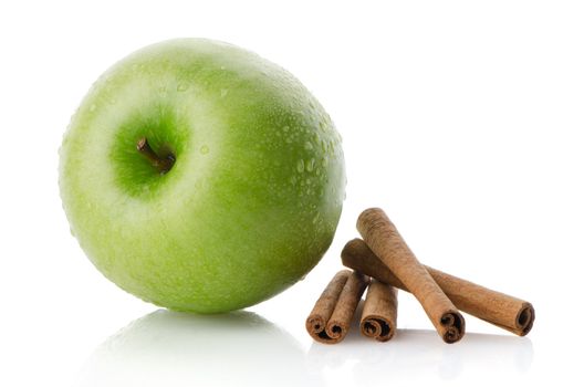 Ripe green apple with cinnamon sticks over reflective white background
