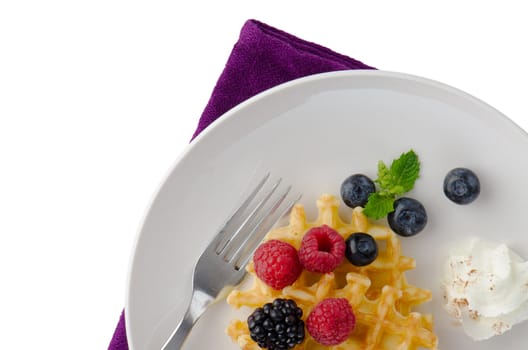 Waffles with fresh berries on white ceramic plate.