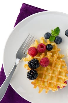 Waffles with fresh berries on white ceramic plate.