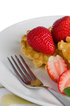 Belgium waffles with strawberries on plate.
