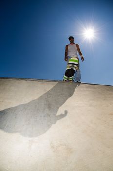 Skateboarder in a concrete pool at skatepark on a sunny day.