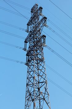 Power lines and electricity pylon  against blue sky