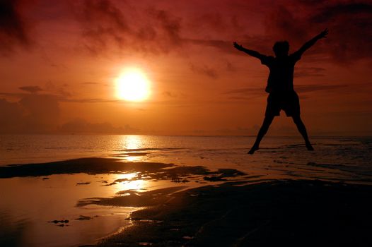 silhouette of a man jumping into the sun photographed by adding a filter gradation                           