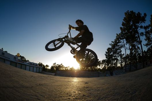 BMX rider jumps while doing cross bar trick.