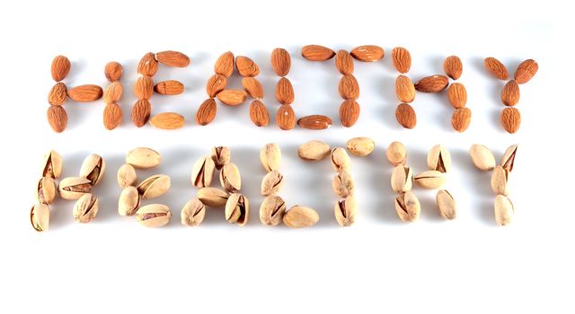 almonds and pistachios composing the word healthy on white background