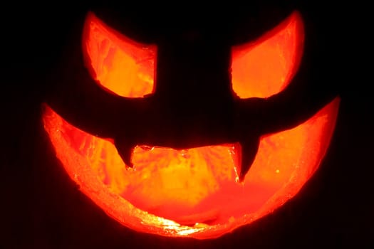 terrifying face made ​​hallowen pumpkin with candle inside illuminating dark background