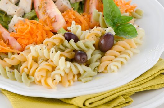 Mixed salad on a white plate and a white wood background.