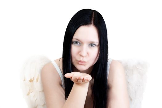 Young blackhaired woman with angel wings blowing some stars on blue background