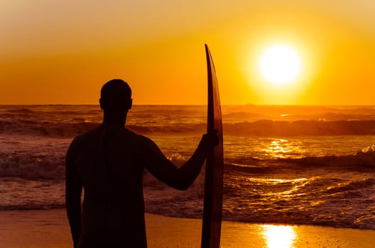 Surfer watching the waves at sunset in Portugal.