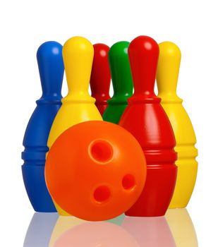 Colorful plastic skittles of toy bowling with orange ball isolated on a white background