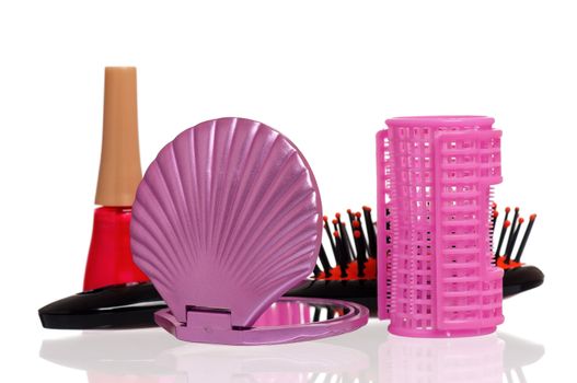 Set of cosmetics - nail polish, hairbrush, hair curlers and small mirror isolated on white background