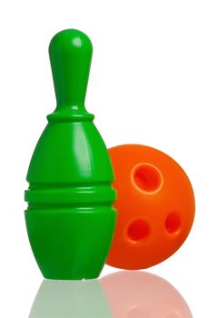 Single plastic skittle of toy bowling with orange ball isolated on a white background