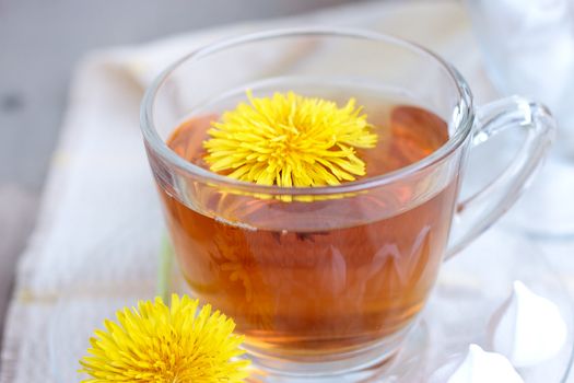 Herbal tea in glass cup and flowers on wooden table