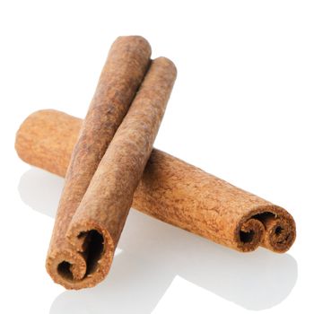 Cinnamon sticks on white reflective background.