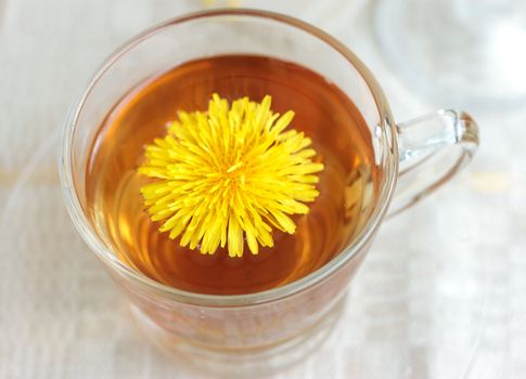 Herbal tea in glass cup and flowers on wooden table