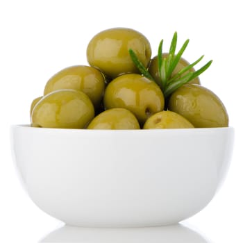 Green olives in a white ceramic bowl on white background.