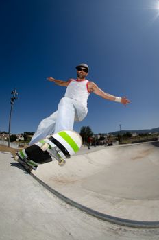 Skateboarder in a concrete pool at skatepark on a sunny day.