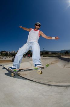 Skateboarder in a concrete pool at skatepark on a sunny day.