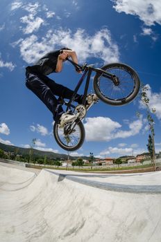 BMX rider jumps while doing cross bar trick.