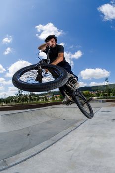 BMX rider jumps while doing cross bar trick.