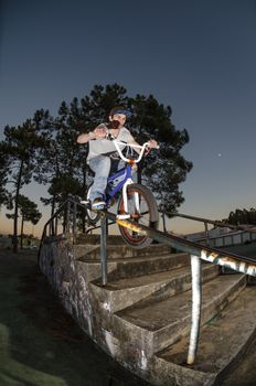 Biker doing peg grind down the hand rail over the stairs