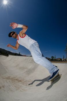 Skateboarder in a concrete pool at skatepark on a sunny day.