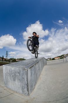 Bmx rider on a ramp over cloudy sky background.