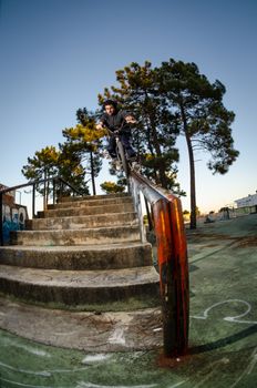 Biker doing peg grind down the hand rail over the stairs