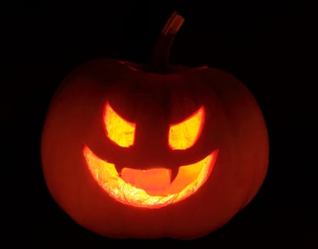 hallowen natural pumpkin with candles inside illuminating dark background