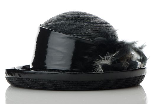 Black vintage hat on white reflective background.
